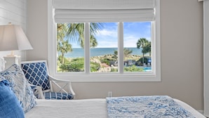 A bedroom with a large window offering a view of the beach and ocean. - Port O' Call D203 - Direct Ocean View! Beach! (Isle of Palms)