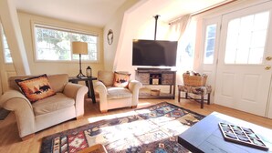 A living room with a sofa, armchairs, a TV, a fireplace, and a patterned rug. - Cozy A-Frame Retreat w/ Views & Spacious Yard (Joseph)
