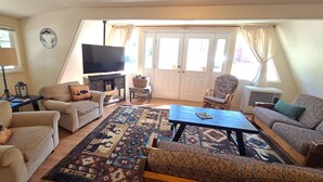 A living room with a TV, sofas, a coffee table, and a patterned rug. - Cozy A-Frame Retreat w/ Views & Spacious Yard (Joseph)