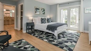 A bedroom with a bed, a nightstand, a ceiling fan, and a view through a sliding glass door.
