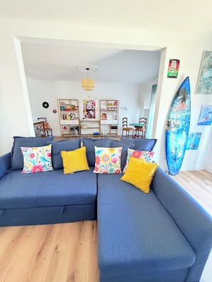 Una sala moderna con un sofá modular, una mesa de comedor y una tabla de surf.