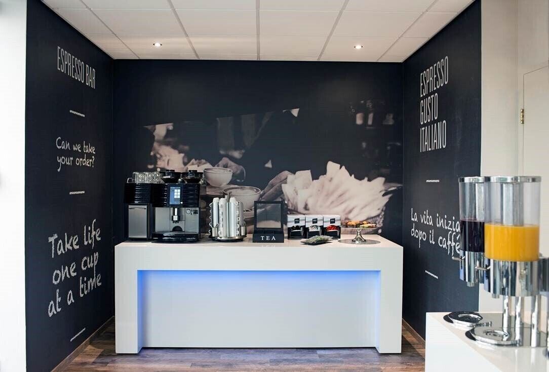 A modern coffee bar with espresso machines, tea dispensers, and a counter.