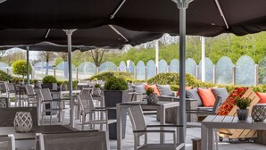 An outdoor patio area with tables and chairs, umbrellas, and potted plants. - De Zoete Inval (Haarlemmerliede)