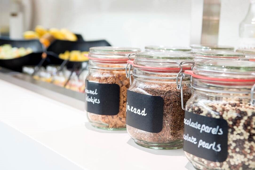 Des bocaux en verre, étiquetés avec les différents types de chocolats, sont disposés sur un comptoir.