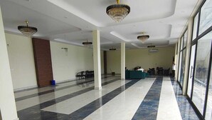 Un hall d’entrée spacieux, doté d’un sol en marbre, de grandes fenêtres et de lustres.