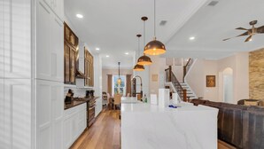 A spacious kitchen with white cabinetry, a marble island, and pendant lighting. - Ultimate Disney Experience PLUS MORE!  (Kissimmee)