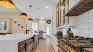 A modern kitchen with a central island, stainless steel appliances, and pendant lighting. - Ultimate Disney Experience PLUS MORE!  (Kissimmee)