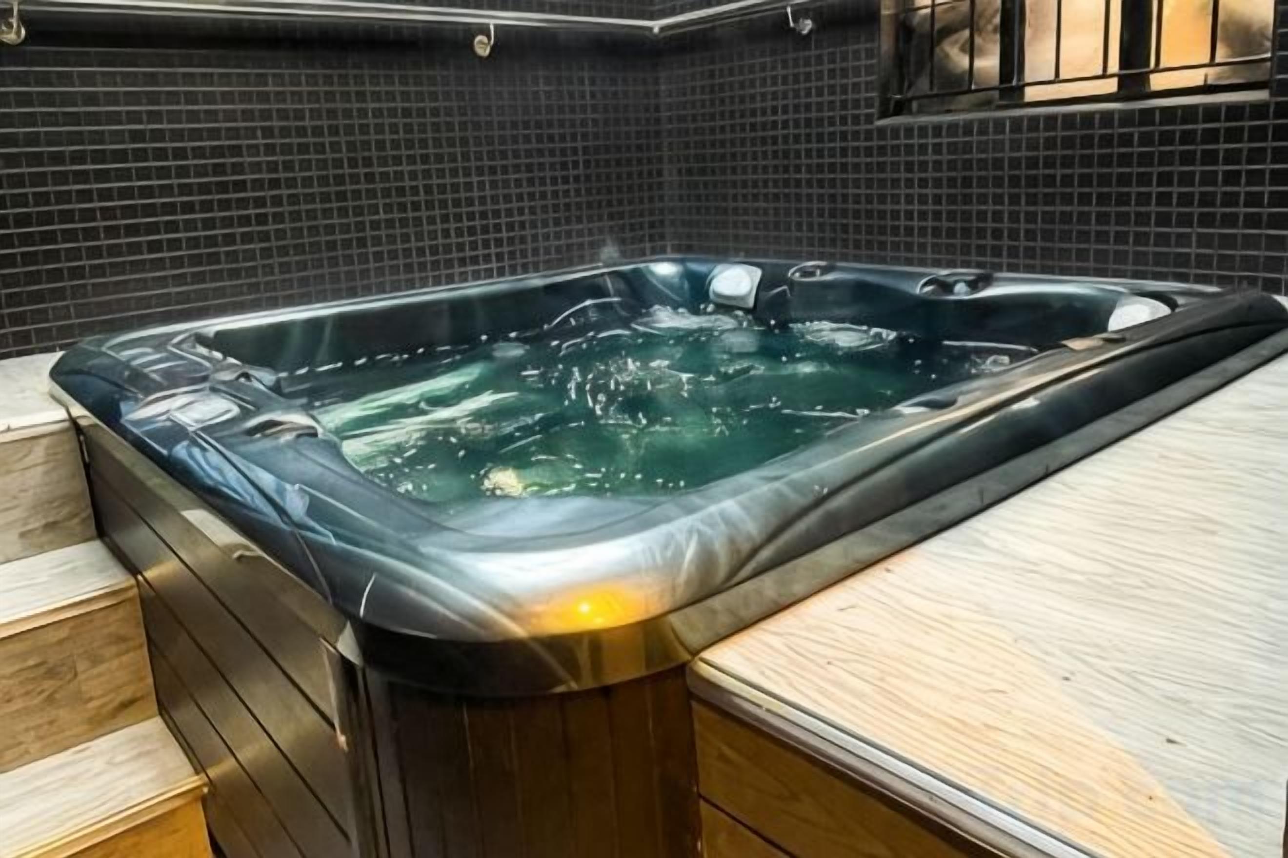 A hot tub with a wooden bench and steps leading into it.