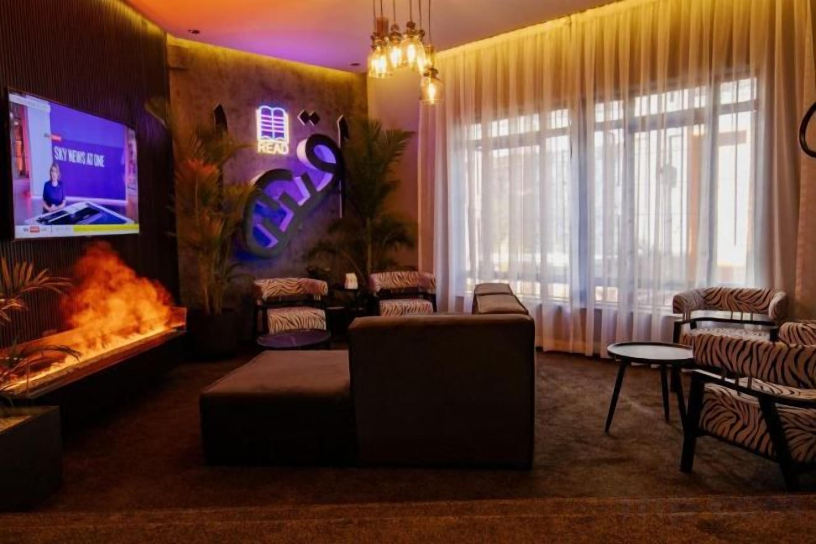 Una sala de estar moderna con chimenea, asientos cómodos, televisor y ventanas amplias.