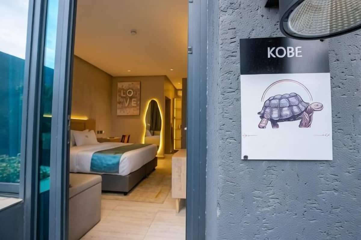 Une chambre à coucher comprenant un lit, une table de chevet, une œuvre d’art accrochée au mur et un panneau illustré avec une tortue.