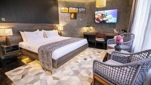 A modern hotel room with a large bed, a desk, a chair, and a TV mounted on the wall. - Gigiri Lion Villas II (Nairobi)