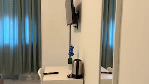 A modern hotel room with a white desk, a mounted TV, a small potted plant, and a large mirror. - United Residence (Mestre)