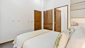 Un dormitorio con una cama, un armario de madera y un estante con toallas enrolladas.