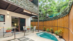 Un patio trasero con una piscina pequeña, cercado por una valla de madera y decorado con plantas en macetas.