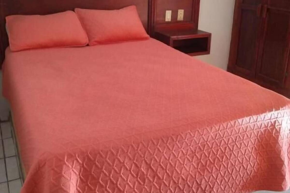 Ein Bett mit Holz-Kopfteil, zwei Nachttische und ein Kleiderschrank.