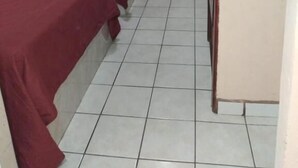 Une chambre avec deux lits, une télévision, un appareil de climatisation et une porte.