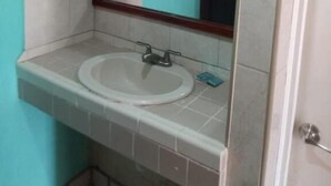 Une salle de bain avec un lavabo blanc, un miroir et une porte.