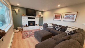 A living room with a fireplace, a sofa, a rug, and a wall-mounted TV.