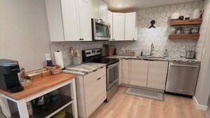 A modern kitchen with white cabinets, a microwave, stove, and dishwasher.