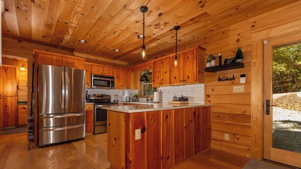 Une cuisine moderne avec des meubles en bois, des appareils électroménagers en acier inoxydable et un îlot central.