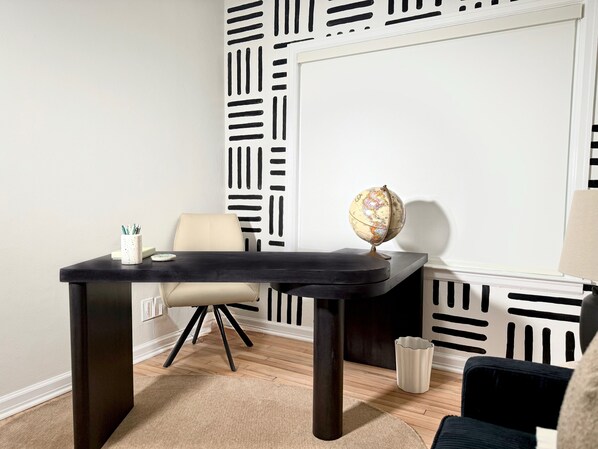 A room with a desk, chair, globe, and patterned wall.