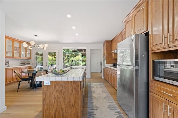 Una cocina moderna con armarios de madera, un refrigerador de acero inoxidable y una isla central.