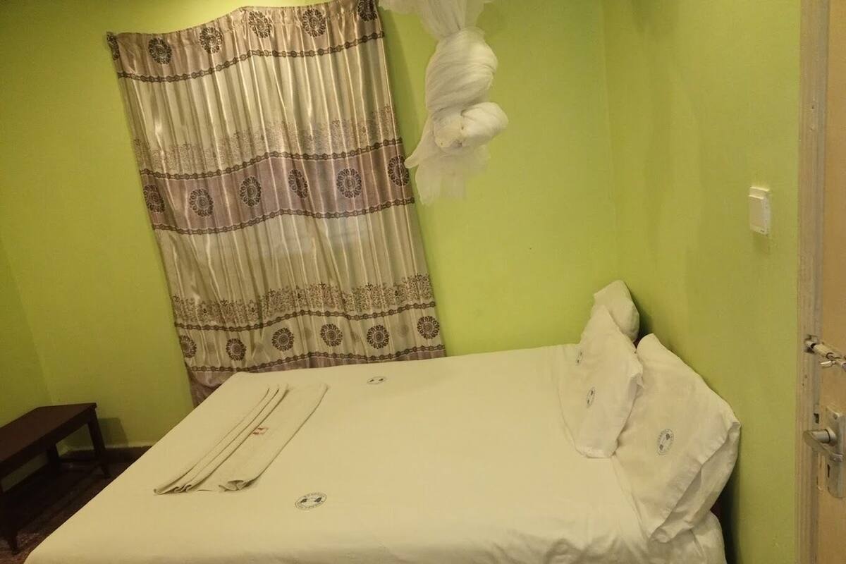 Una habitación con una cama, una cortina y una puerta.