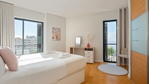 Ein modernes Hotelzimmer mit einem großen Bett, einem Schreibtisch und Blick auf die Stadt.