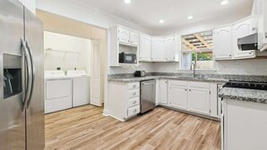 Une cuisine moderne avec des meubles blancs, un réfrigérateur en acier inoxydable, un four à micro-ondes et une cuisinière.
