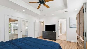 Une chambre avec un grand lit, un ventilateur de plafond, une télévision et une armoire.