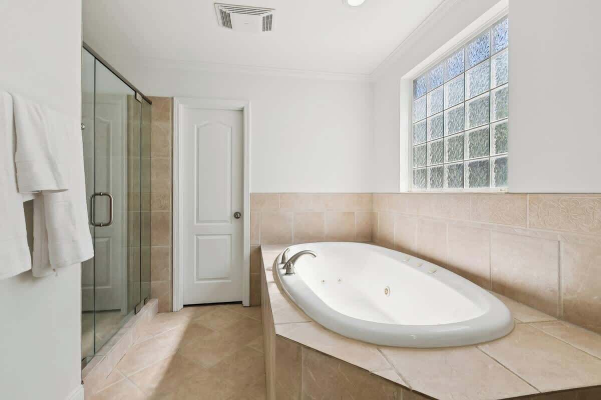 Un bagno con una vasca freestanding, cabina doccia in vetro e finestra con vetro smerigliato.