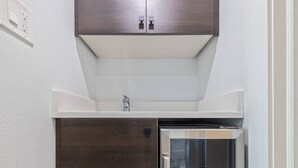 Una cocina compacta con horno empotrado, microondas y refrigerador de acero inoxidable.