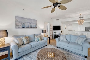 A modern living room with two sofas, a coffee table, and a ceiling fan.