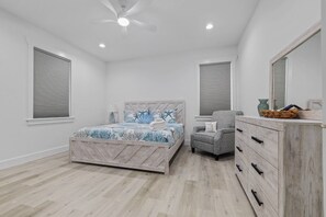 A bedroom with a bed, a chair, a dresser, and a ceiling fan.