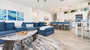A modern living room with a sectional sofa, a marble coffee table, and a patterned rug.