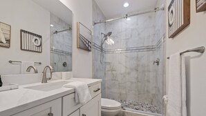 A modern bathroom with a glass-enclosed shower, a white sink, and a toilet.