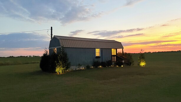 A small, single-story barn with a sloped roof, a porch, and a small attached shed. - Cozy Cottage 1bed 1bath in Slocomb Al (Slocomb)