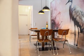 A dining area with a table, chairs, pendant lights, and a wall mural. - Suites at the Historic Berghotel Johanna (Eslohe (Sauerland))