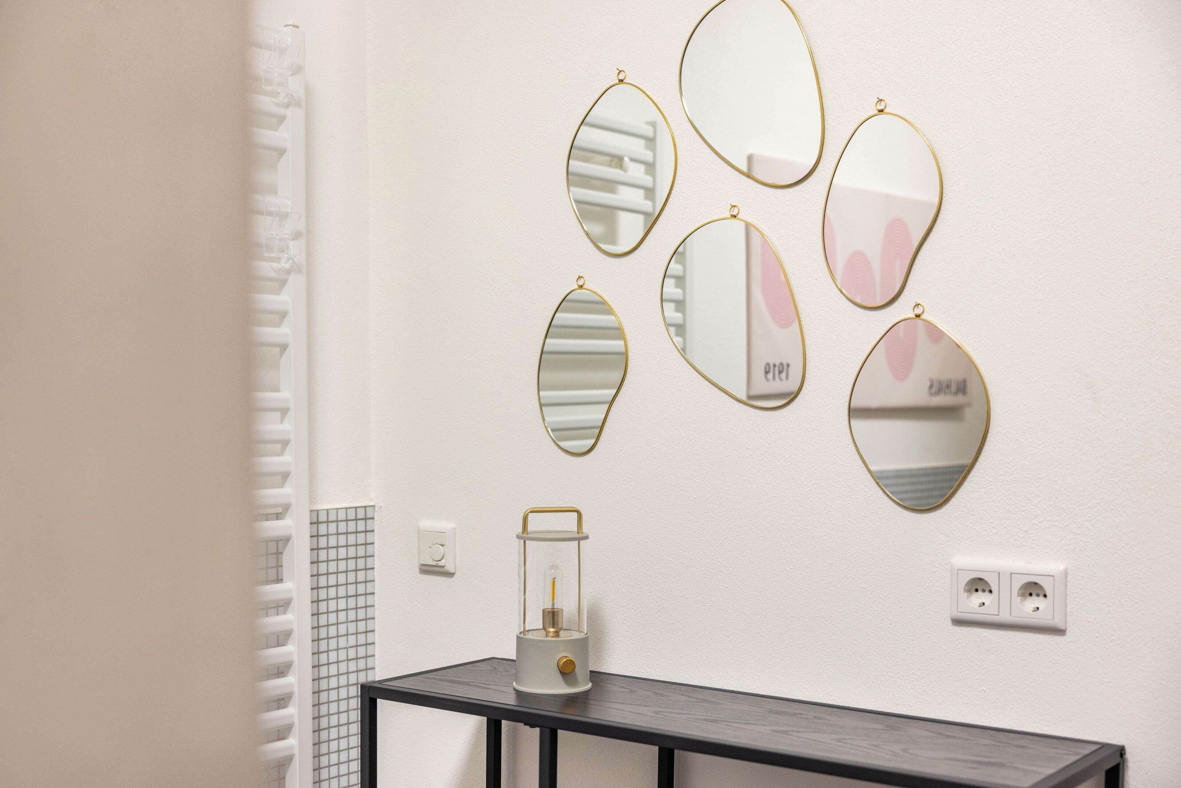 Ein Badezimmer mit Spiegelwand, einem kleinen Tisch mit Lampe und einem Handtuchhalter.