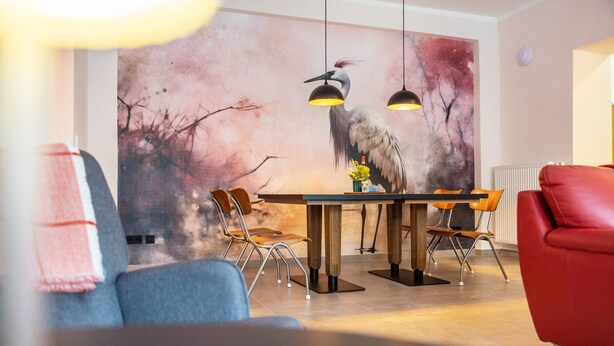 Un espace repas agrémenté d’une fresque murale, d’une table en bois et de chaises modernes.