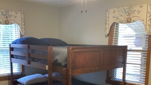 Ein Stockbett mit Holzbettrahmen und einem Deckenventilator darüber.