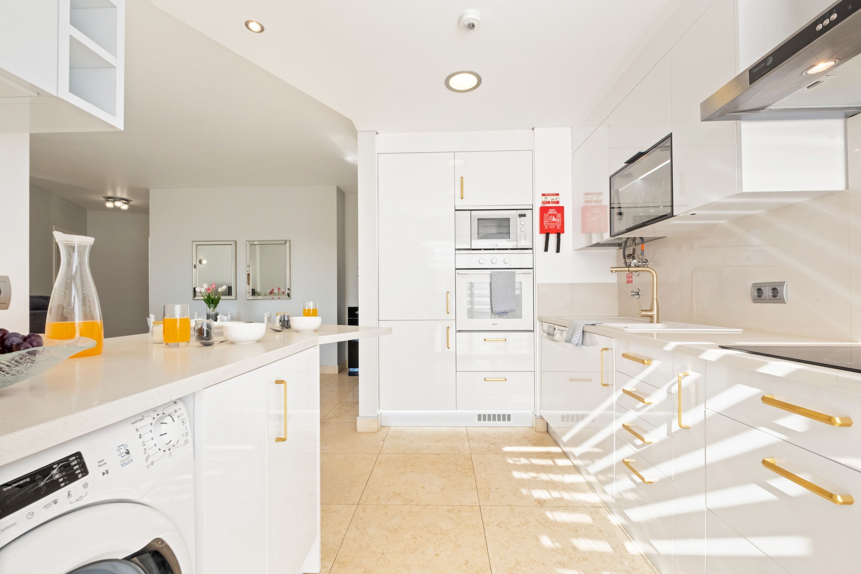 A modern kitchen with white cabinetry, a built-in oven, microwave, and a coffee machine.
