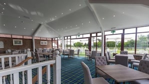 A restaurant with a high ceiling, large windows, and a checkered floor. - Dale Hill Hotel (Ticehurst)