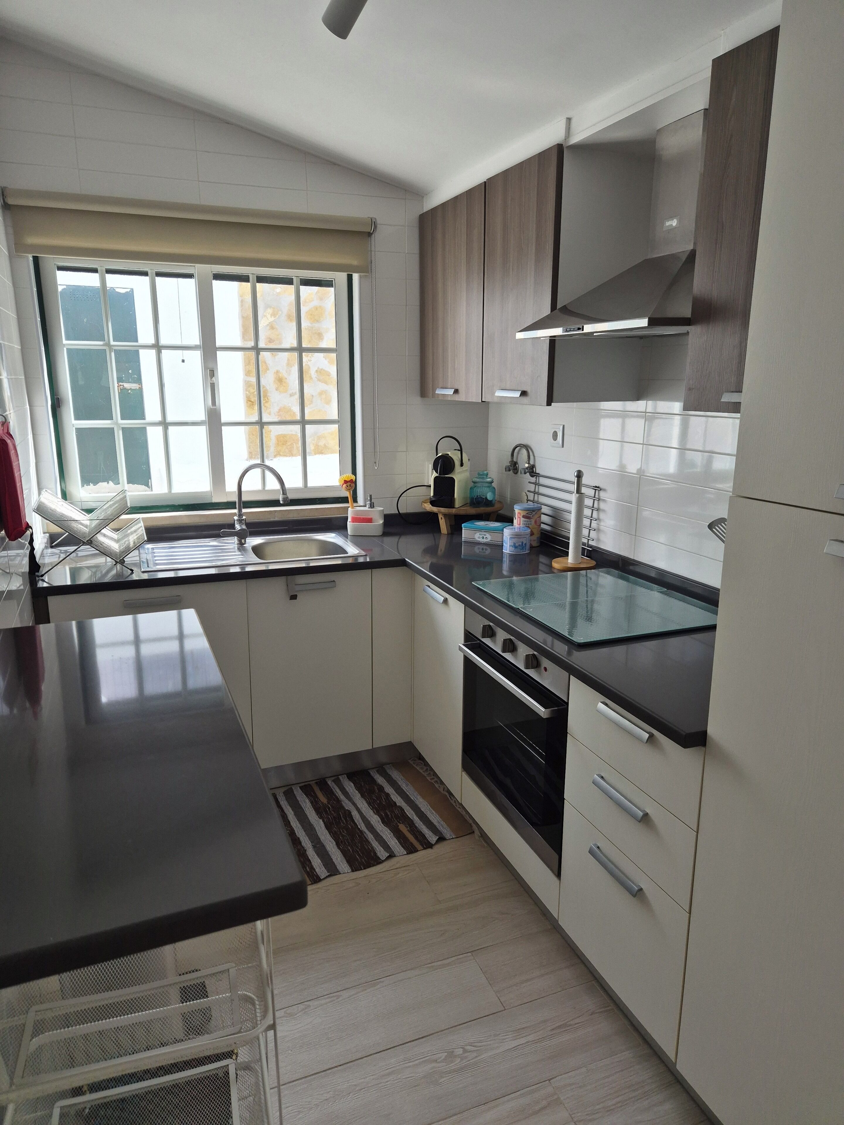 A modern kitchen with a stainless steel sink, a built-in oven, and a large window with a view.