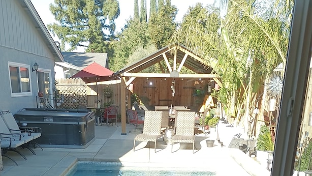 A view of a backyard with a swimming pool, patio furniture, and a covered seating area. - Lovely studio in Sacramento near downtown. (Sacramento)