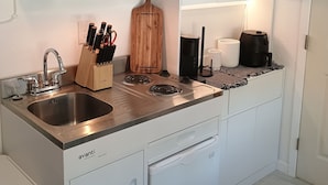 A compact kitchen with a built-in microwave, a sink, a stovetop, and a dishwasher. - Lovely studio in Sacramento near downtown. (Sacramento)
