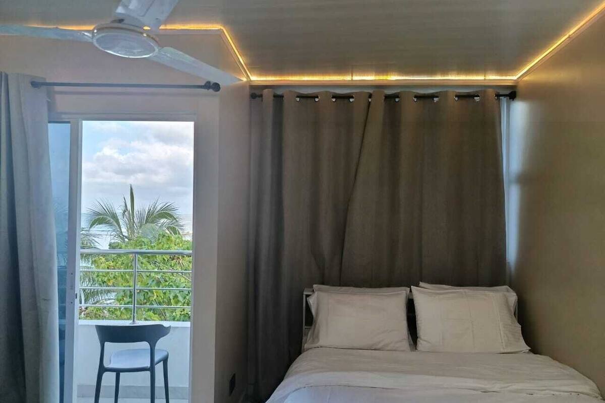 A bedroom with a bed, curtains, and a view of greenery outside.