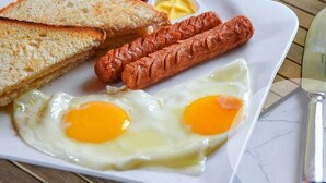 En frukosttallrik med rostat bröd, korv och stekt ägg.