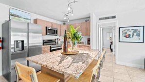 A modern kitchen with stainless steel appliances, a marble countertop, and a central island with seating.