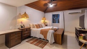 A bedroom with a bed, bedside tables, a desk, a chair, and a ceiling fan.